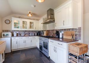 a kitchen with white cabinets and a stove top oven at Blossom Cottage in Lakenheath