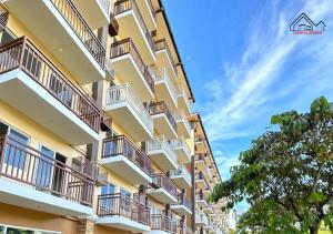 a tall apartment building with balconies and a tree at Affordable Vacation Rental with FREE Pool, Gym and Parking near Puerto Princesa -7Topaz in Puerto Princesa City