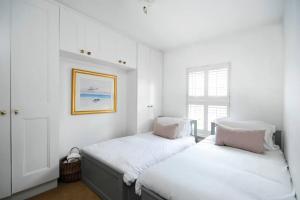 a white room with two beds and a window at Ivy Cottage in Henley on Thames