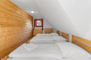 fila de 4 camas en una habitación con paredes de madera en Chata Kukaňa, en Stará Lesná