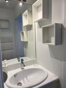 een witte badkamer met een wastafel en een spiegel bij Le Balbec - Appartement Cosy in Cabourg