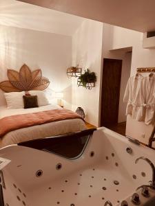 1 dormitorio con cama y bañera en La Petite Grange - Spa Balnéo en Vigneux-de-Bretagne