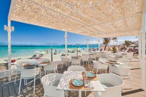 um restaurante na praia com mesas e cadeiras em The Sea Hotel by Grupotel - Adults Only em Can Picafort