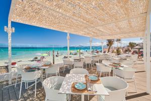 ein Restaurant am Strand mit Tischen und Stühlen in der Unterkunft The Sea Hotel by Grupotel - Adults Only in Can Picafort