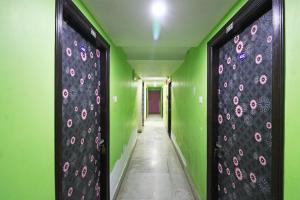 a corridor with green walls and black and pink flowers at Xpress Inn in Garui