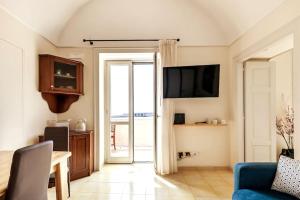 ein Wohnzimmer mit einem TV und einem blauen Sofa in der Unterkunft Casa del pozzo sulla spiaggia in Cetara