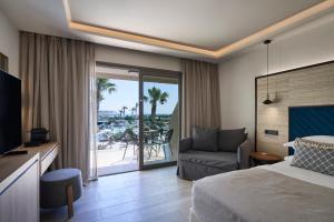 a hotel room with a bed and a couch and a balcony at Atlantica Aegean Blue in Kolimbia