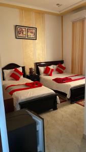 Habitación de hotel con 2 camas con almohadas rojas en Hotel Biarritz, en Tánger