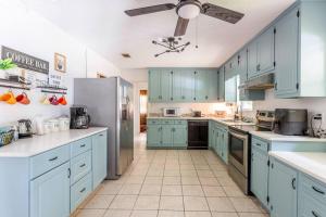 a kitchen with blue cabinets and a refrigerator at Golden Isles Lrge Home- Huge Pool, Hot Tub, Game Rm in Brunswick