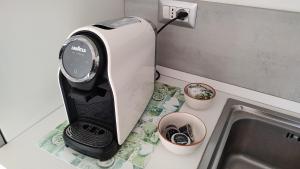 una macchinetta del caffè seduta su un bancone accanto a un lavandino di Memento a Ossi