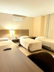 a hotel room with two beds and a table at Umbu Hotel Porto Alegre - Centro Histórico - Prox Aeroporto 15min in Porto Alegre