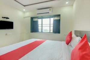 Un dormitorio con una cama con almohadas rojas y una ventana en OYO Villa 31 en Akot
