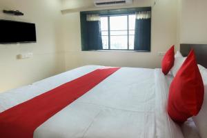 1 dormitorio con 1 cama grande con almohadas rojas en OYO Villa 31 en Akot