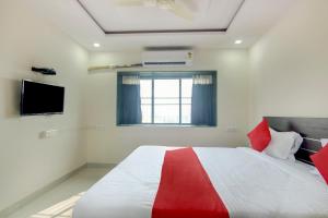 1 dormitorio con 1 cama roja y blanca y TV en OYO Villa 31 en Akot