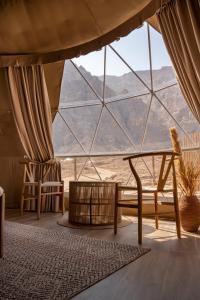 um quarto com uma grande janela com uma mesa e cadeiras em Pura Eco Retreat, Jebel Hafit Desert Park em Al Ain