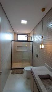 baño con aseo y ducha y ventana en Mansão Quinta dos Ventos, en Ribeirão Preto