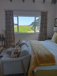 a bedroom with a bed and a couch and a window at 19, Ridge House in St Francis Bay