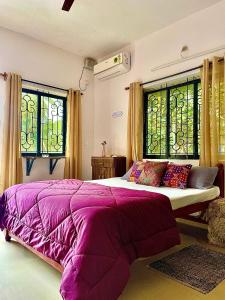 uma cama roxa num quarto com janelas em Mitra Homes - Mandrem em Mandrem