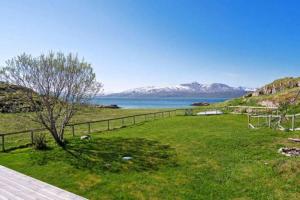 a field with a fence and a view of the water at Idyllic and peaceful Family Home in Tromsø