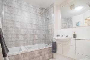 a bathroom with a tub and a sink and a bath tubermottermott at Garden View Nook-2 bed apartment in High Blantyre