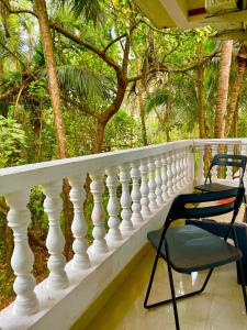 a white balcony with two chairs and trees at Mitra Homes - Mandrem in Mandrem