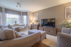 Una sala de estar con un sofá y un televisor de pantalla plana. en Garden View Nook-2 bed apartment, en High Blantyre