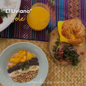 Una mesa con un tazón de comida y un vaso de jugo de naranja. en Hostal Sole, en Santa Ana