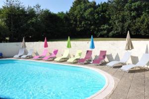 un grupo de sillas y sombrillas junto a una piscina en Jade - Gîtes De Kerlividic en Ploërdut