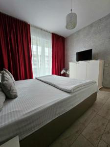 a bedroom with a large bed with red curtains at Sunrise Residence in Mamaia Sat/Năvodari