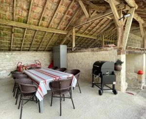 eine Terrasse mit einem Tisch, Stühlen und einem Grill in der Unterkunft Lassegues in Castetner