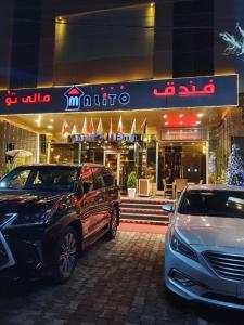 two cars parked in front of a store at night at Malito in Erbil