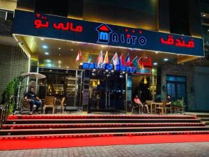 a man sitting on a bench in front of a restaurant at Malito in Erbil