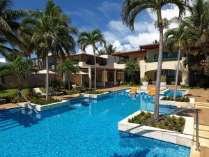 a swimming pool with palm trees in front of a building at Azul Villa Casa del Mar - Gourmet All Inclusive by Karisma in Puerto Morelos