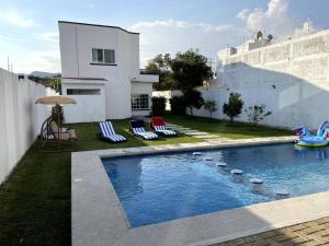 a swimming pool with chairs and a house at Casa Lycha in Tlayacapan