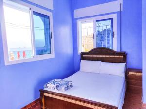 a bed in a blue room with two windows at Dar Khairoun with Balcony in Chefchaouene