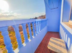 a balcony with a blue railing and a chair at Dar Khairoun with Balcony in Chefchaouene