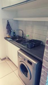 a kitchen with a sink and a washing machine at Wild Olive Inn 62 in Windhoek