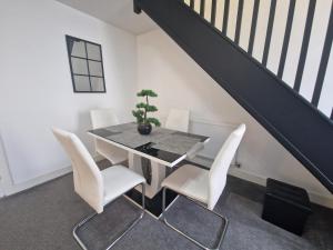 a dining room with a black table and white chairs at 3 bedroom modern house. Merthyr Tydfil near bike park wales and Brecon Beacons National park in Dowlais