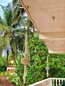 a hammock hanging from a porch with a palm tree at Mitra Homes - Mandrem in Mandrem