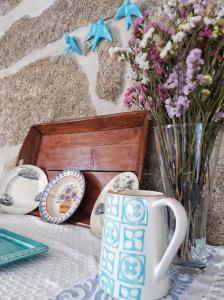 einen Tisch mit einer Tasse und einer Vase Blumen in der Unterkunft Casa do Soito in Oliveira do Hospital