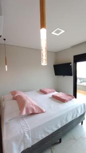 - une chambre dotée d'un lit avec des oreillers roses dans l'établissement Mansão Quinta dos Ventos, à Ribeirão Preto