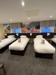 a room with four beds in a room with paintings at Buccleuch Arms Hotel in Moffat