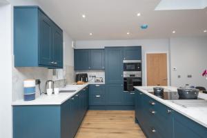 una cocina con armarios azules y encimeras blancas en Historical Holmehill Lodge, en Dunblane