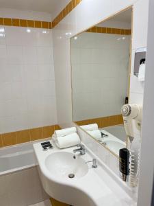een badkamer met een wastafel, een spiegel en een bad bij Hotel Royal in Praag