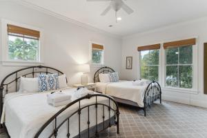 two beds in a room with two windows at 1002 E Cooper The Folly Peach Beautiful Spacious House Steps from the beach in Folly Beach