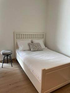 een bed met een kussen en een kruk in een kamer bij Mont-sur-Lausanne: Studio très cosy ! in Le Mont-sur-Lausanne