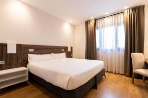 a bedroom with a large white bed and a chair at Alda Ruta Castilla in Palencia