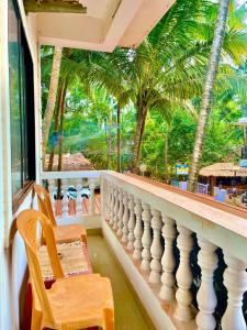a balcony with a table and chairs and palm trees at Mitra Homes - Mandrem in Mandrem