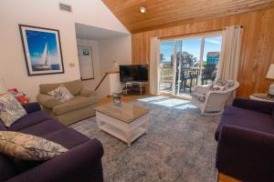 un soggiorno con un divano e una TV di Semi-Oceanfront, Private Pool, Poolside Bar, Hot Tub, Ocean Views! T1, Sailaway a Duck