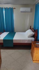 a bedroom with a large bed with blue curtains at Manderley Villas in Saint Philip